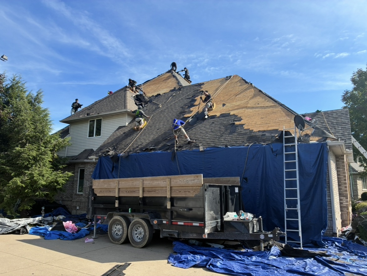 Milo's crew removing shingles from the roof with protective tarps around the home
