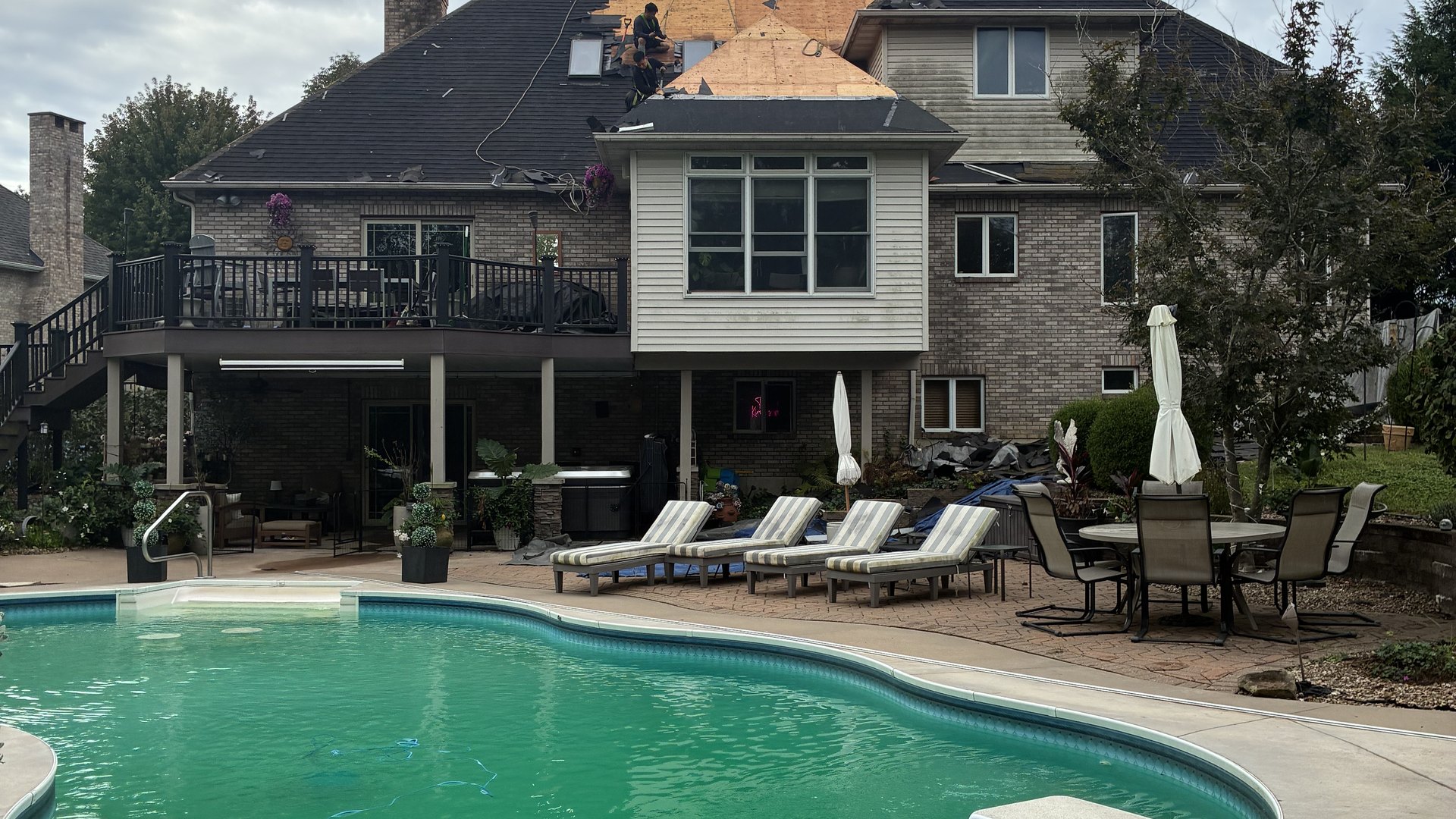 Milo's crew replacing the roof on a two-story home beside a backyard pool
