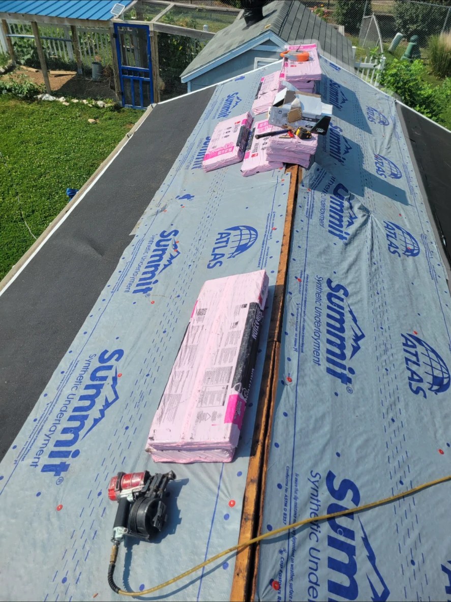 Synthetic underlayment installed on a roof deck with shingle bundles staged