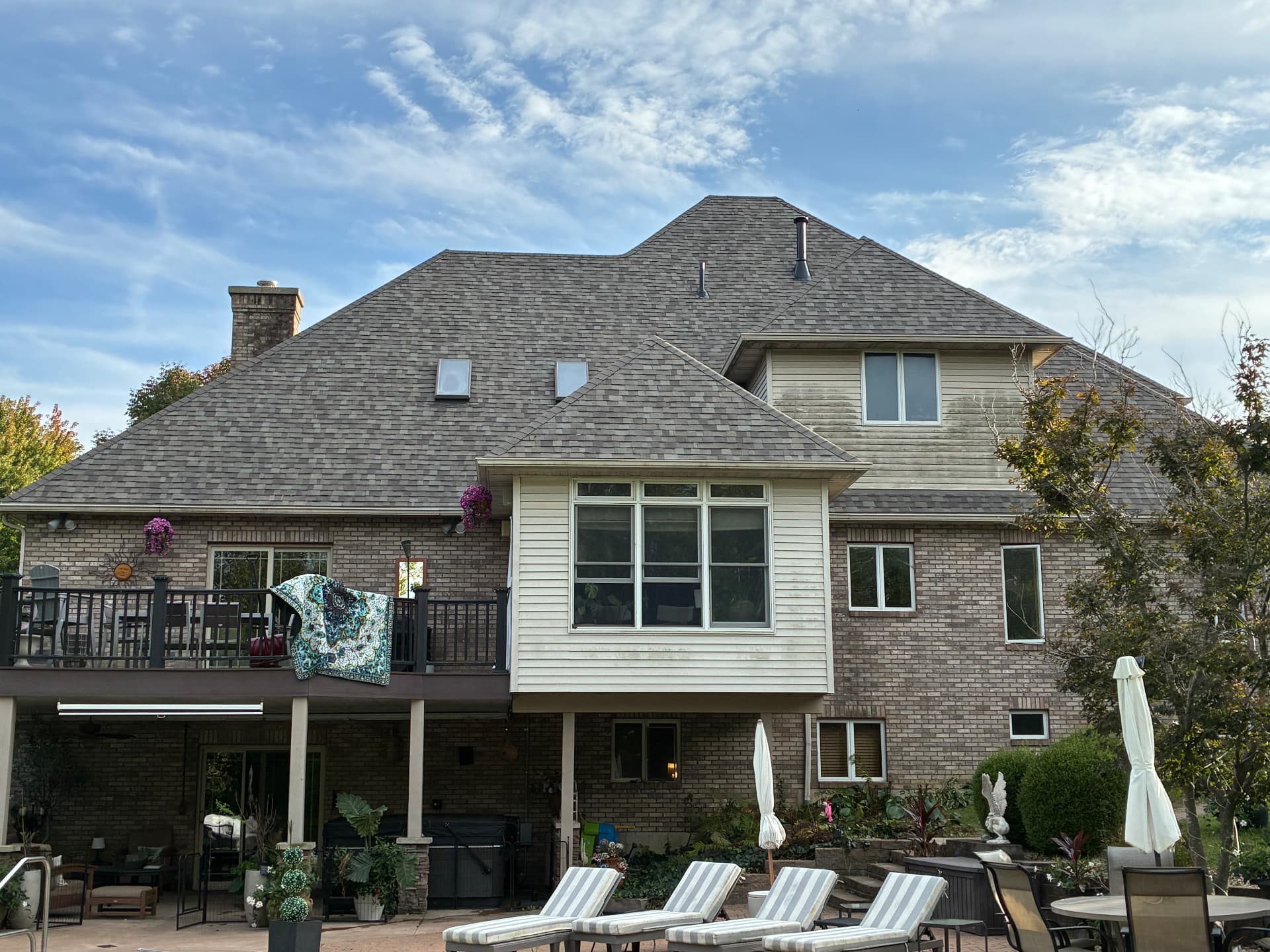Finished shingle roof on a two-story brick home seen from the backyard deck and pool