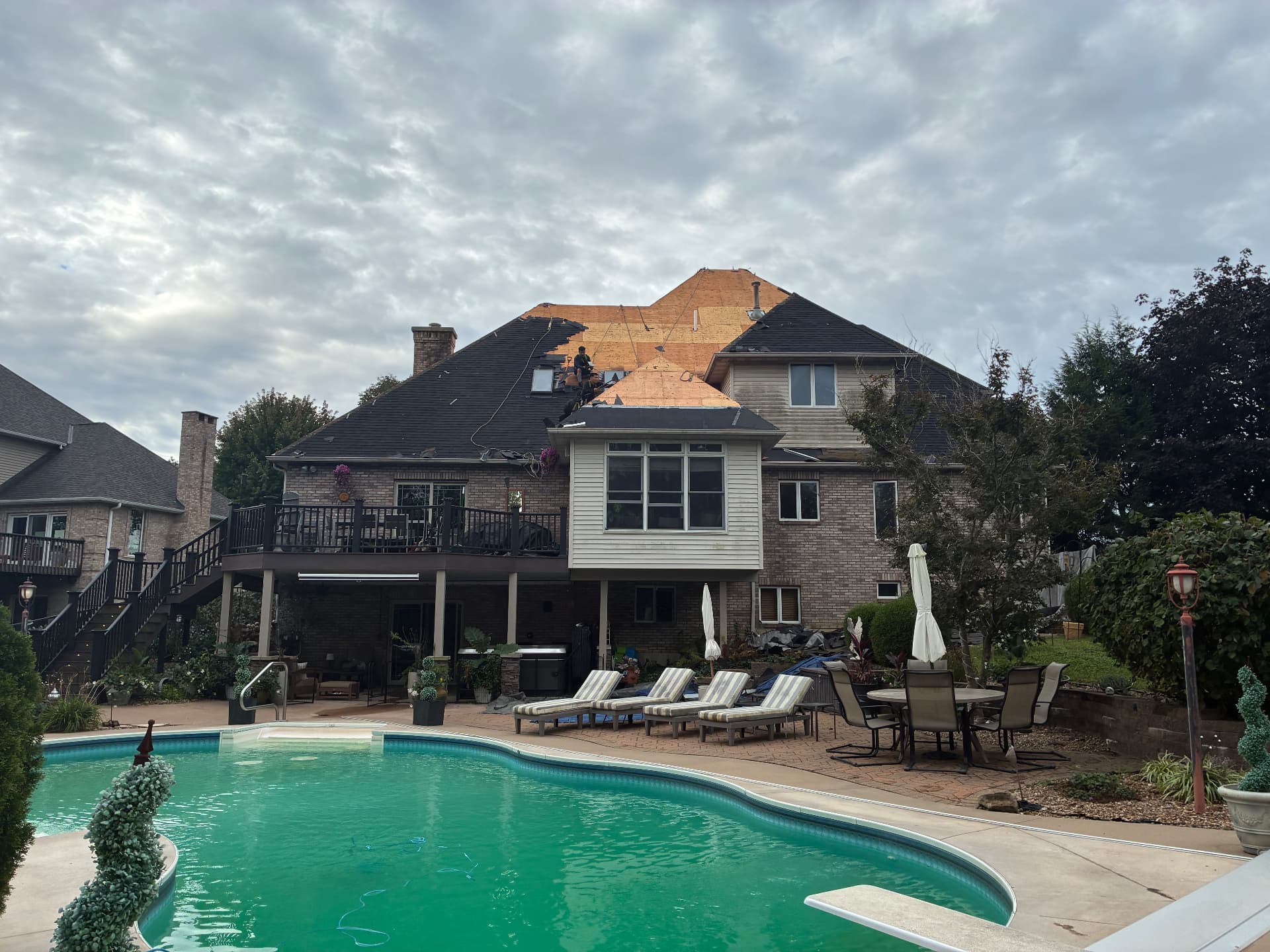 Roof replacement in progress with exposed wood decking above a backyard pool